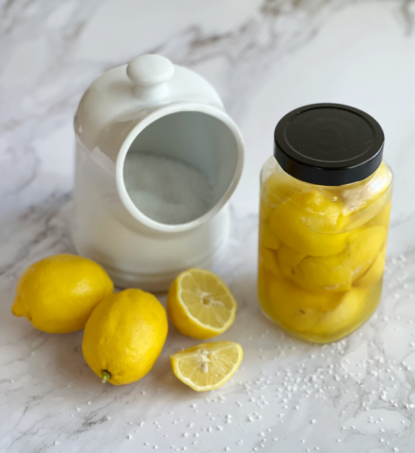 Lemons, white salt pig and a jar of preserved lemons.