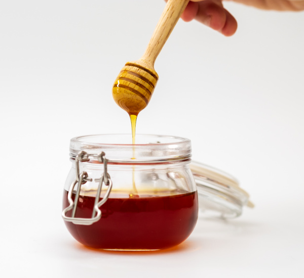 honey in a jar with a honey stick. 