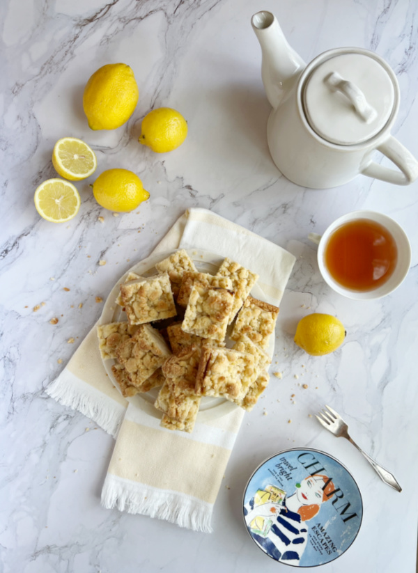 Lemon crumb bars flatlay with tea, tea pot and colorful plates. 