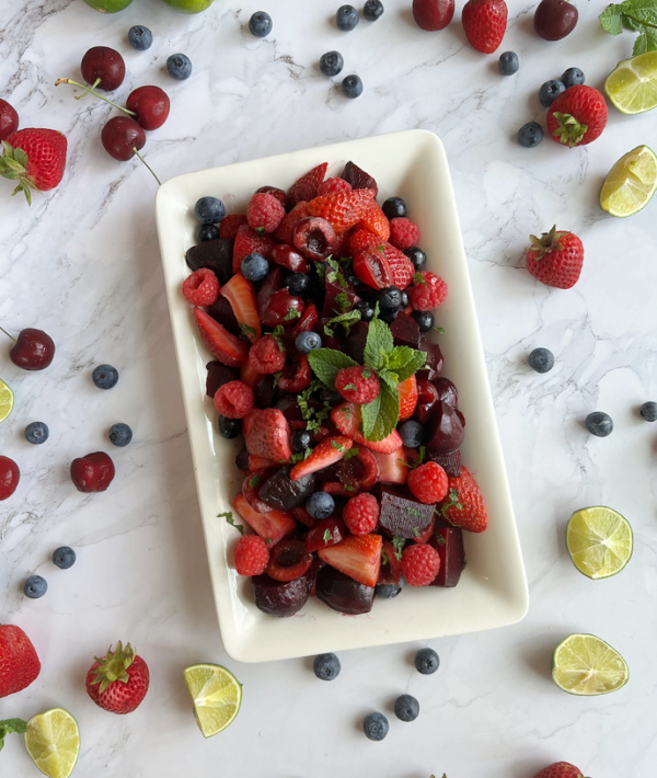 beet fruit salad on a white platter with scattered fruit. 