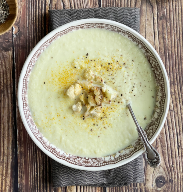 bowl of cauliflower soup with crusty bread and a spoon. 