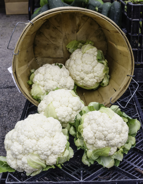 cauliflower heads in a wooden basket.
