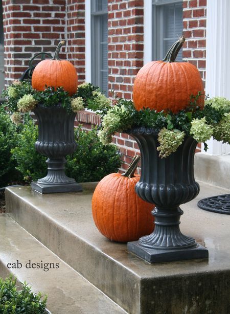 Black urns topped with pumpkins. 