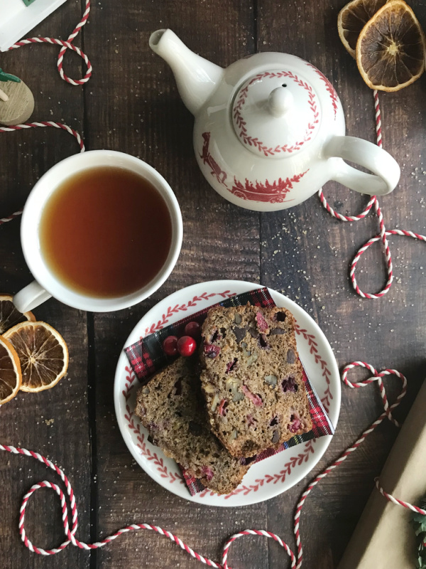 Cranberry apple Bread with sliced dried oranges and a red, and white teapot, cups and saucer.