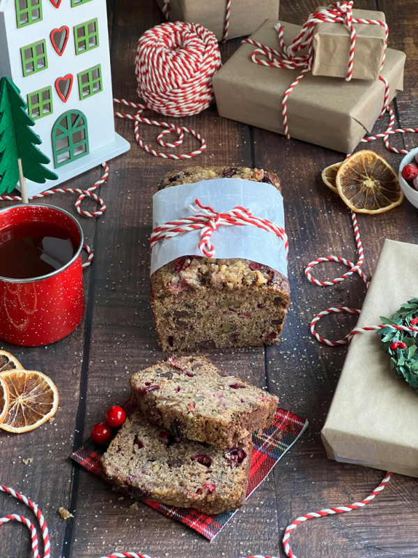 Cranberry apple Bread with sliced dried oranges and a red, green and White House and brown wrapped packages.