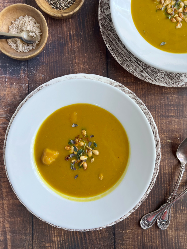 a white bowl of soup and spoons.