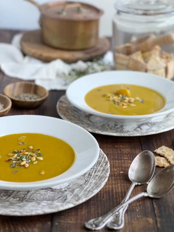 butternut squash soup and spoons with crackers and a copper pot.