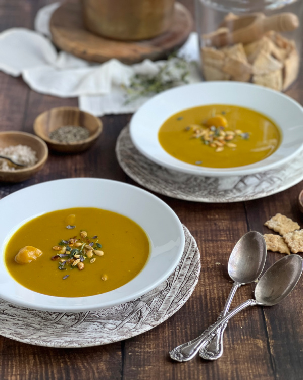 butternut squash soup and spoons with crackers in two white bowls and salt and pepper.