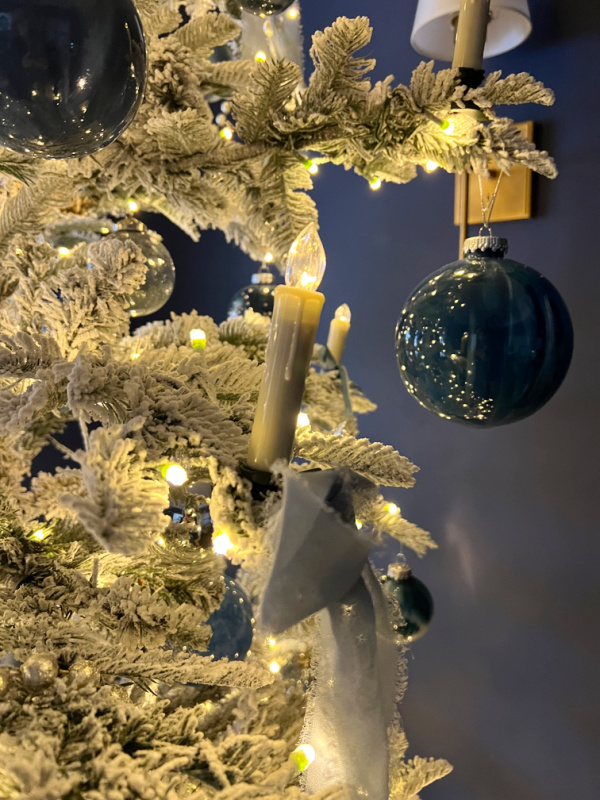 flocked tree with blue ornaments and candle clip on lights.