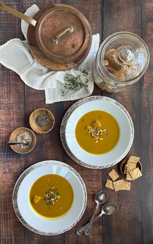 creamy-roasted-butternut-squash-soup-with-a-jar-of-crackers-a-copper-pot-pumpkin seeds-and-thyme