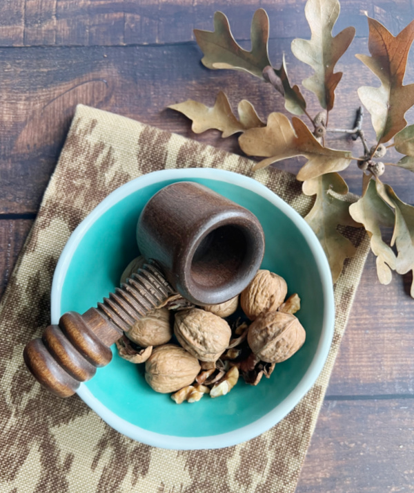 walnuts in a jade green bowl with a wood nut cracker.