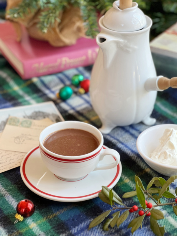 Parisian Hot chocolate in a white cup with christmas ornaments and a book.