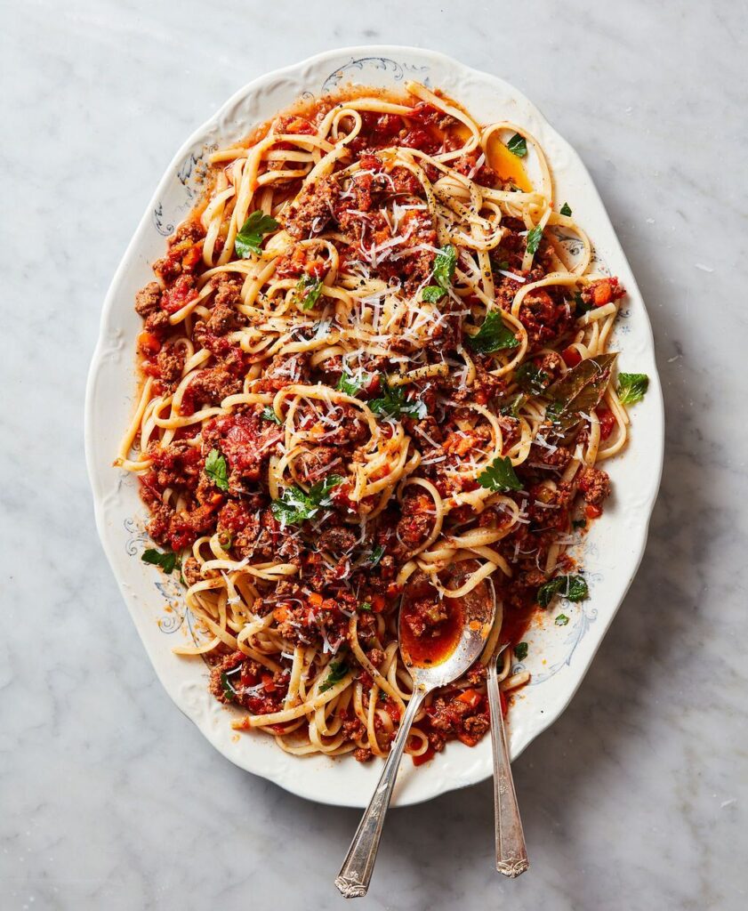 Bolonese pasta on a white platter. 