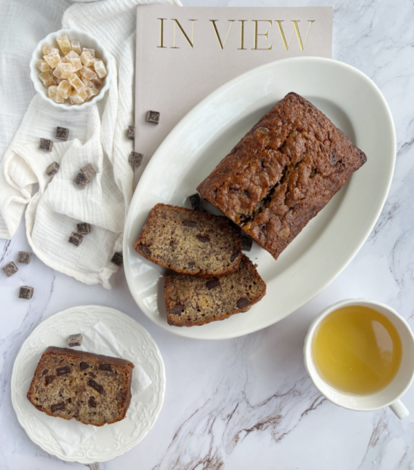 Banana bread sliced on a platter with a cup of tea.