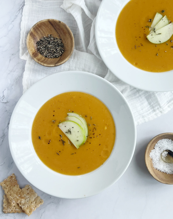 Ina Garten Butternut Squash and Apple Soup in white bowls with salt and pepper.