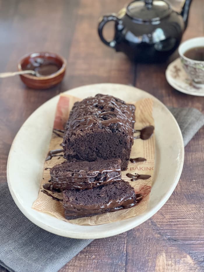 Chocolate bread-sitting on a white ironstone platter with a cup of tea dan a brown tea pot.