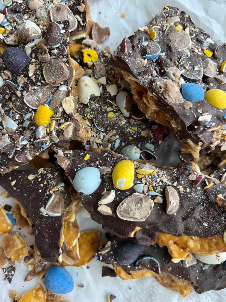 Cadbury mini egg pretzel toffee broken into pieces on parchment paper