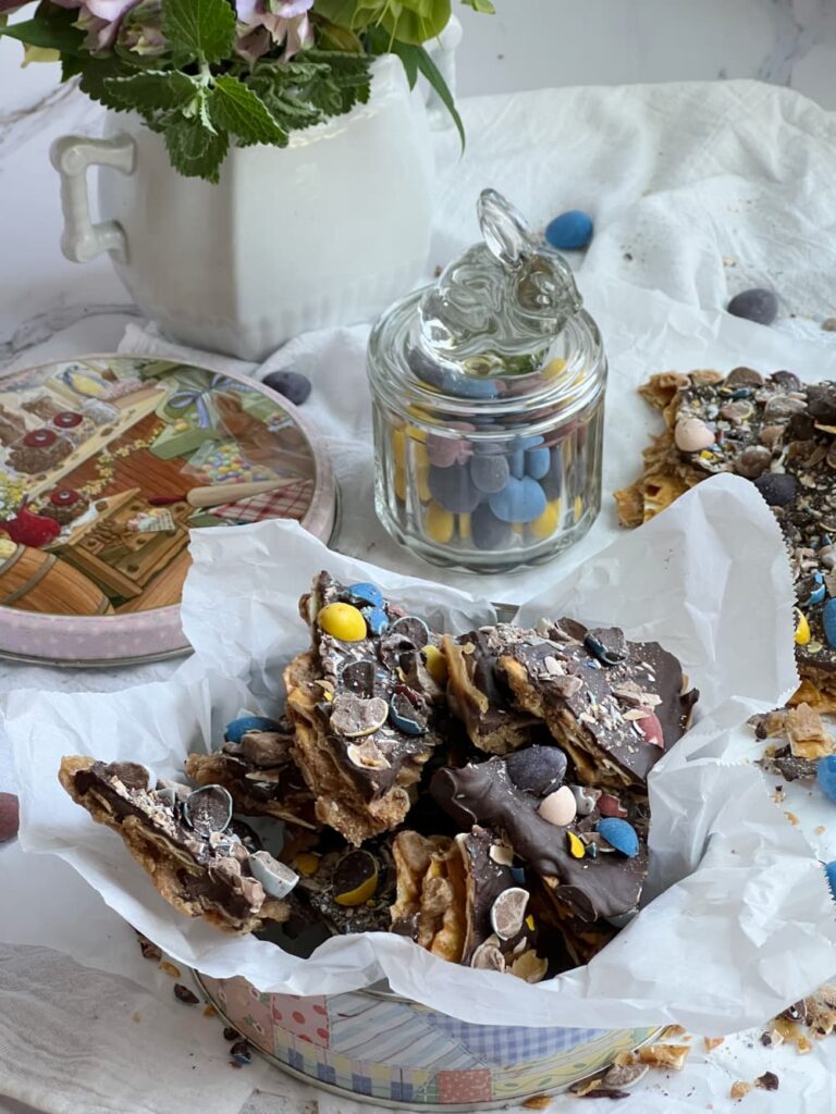 Easter toffee in a tin with a clear glass jar of Easter candy with a bunny top