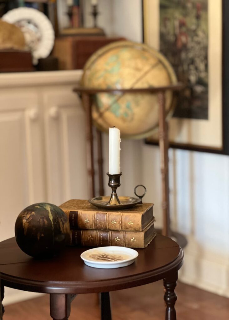 small table leather books globe and candle.