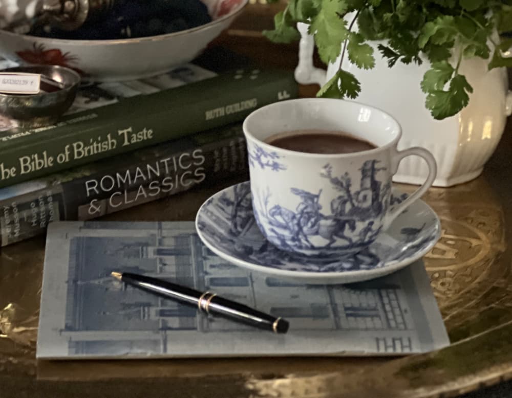 Morning ritual after 50 — toile cup of drinking chocolate gratitude journal and spring greens in a white vase