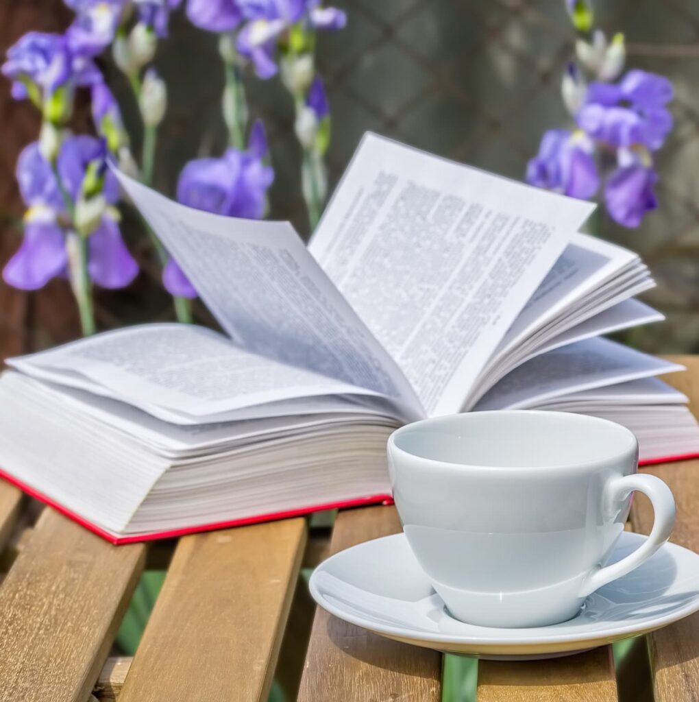 Spring book and a cup of tea with purple iris in the background — Friday Favorites Pinecones and Acorns