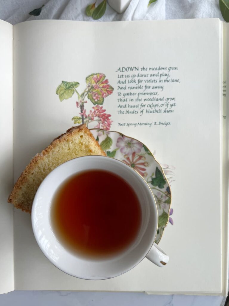 Spring flatlay with a cup of tea poundcake and a book with spring poem