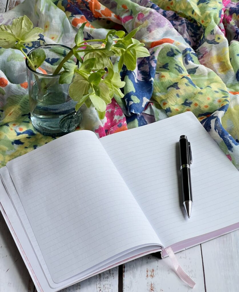 monday musings —hellobores in a glass with a journal pen and colorful scarf