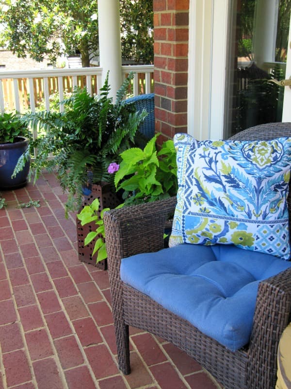 spring porch with wicker furniture and blue and green pillows. 