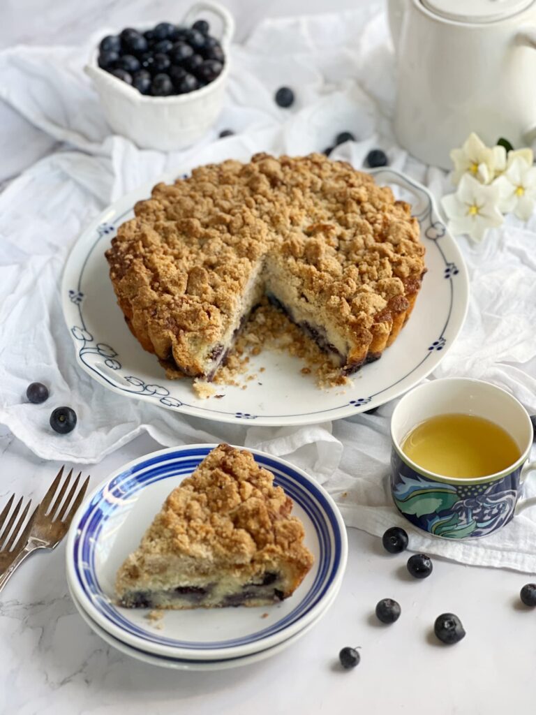 Blueberry Crumb Coffee cake slices with a cup of tea dan a bowl of blueberries