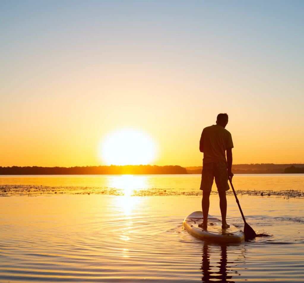 A paddle board on a still lake at golden hour on a summer morning in North Carolina