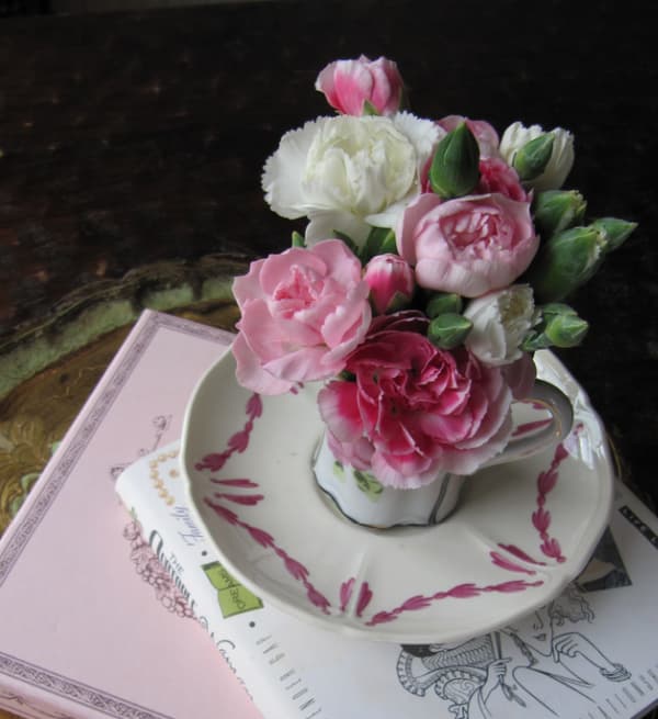 Spring self care ideas- pink-flowers-in-a-tea-cup-on-a-pile-of-pink-and-white-books
