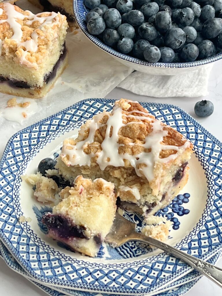 A slice of blueberry coffee cake on a blue and white transfer ware plate