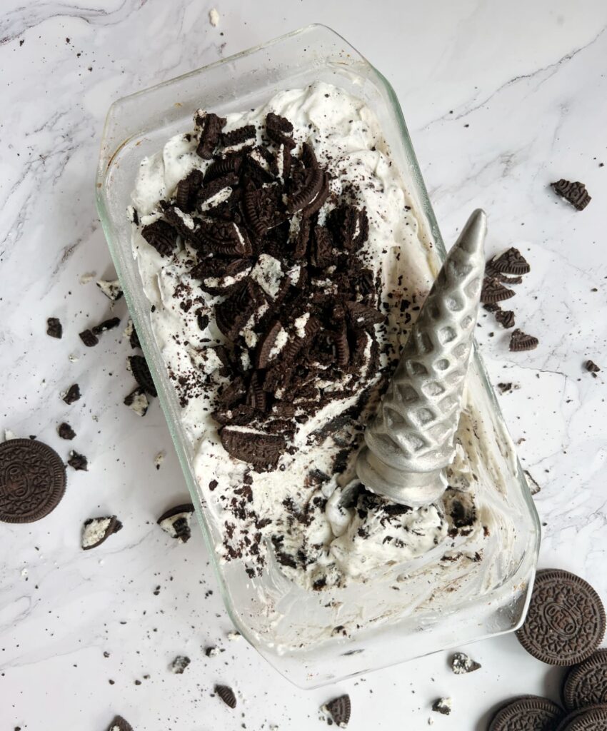 Glass loaf pan of no churn ice cream with an ice cream cone shaped ice cream scoop