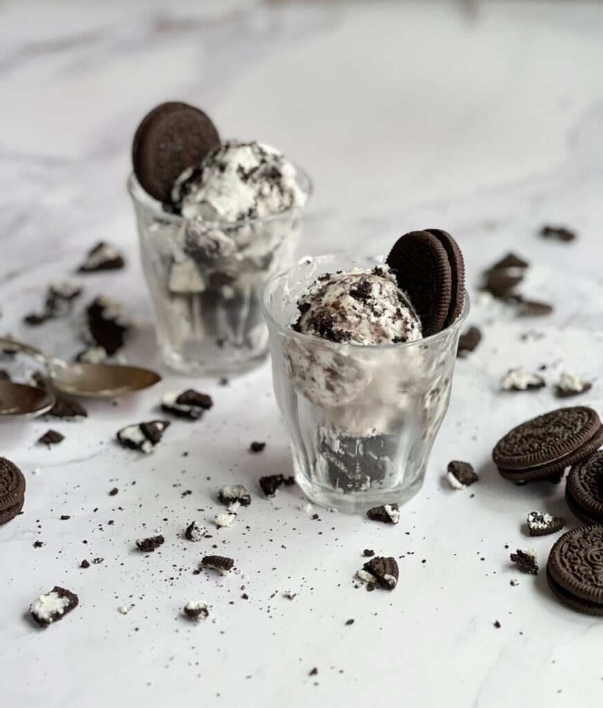 No churn cookies and cream ice cream in glasses with Oreos scattered about