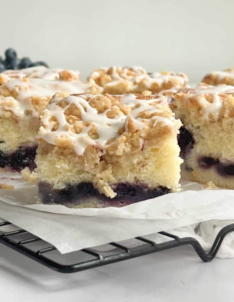 Sliced blueberry coffee cake with crumble topping and a drizzle of icing