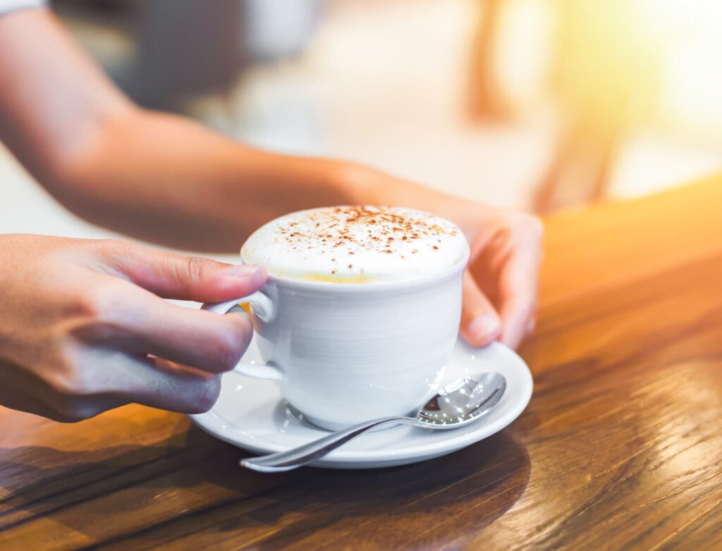 A woman’s hands wrapped around a cup of tea in a quiet morning moment.