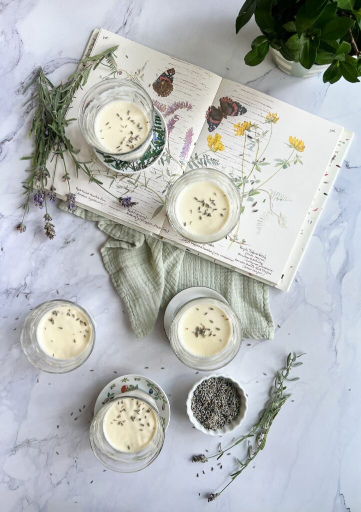 Lavender panna cotta in glasses sitting on a book with springs of lavender