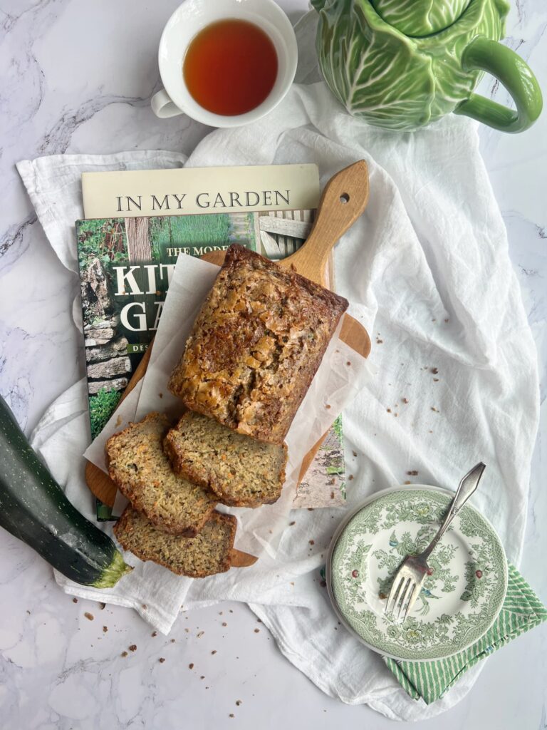 carrot zucchini banana bread sliced on a wood cutting board with a cup of tea