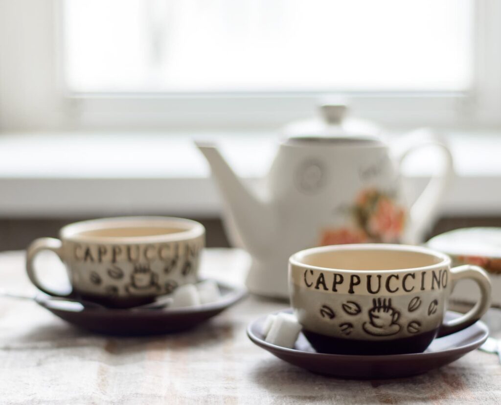 two cups of tea and a teapot on a table in warm morning light