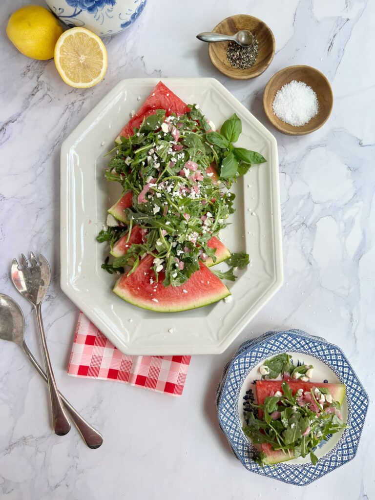 watermelon arugula salad with pickled onions and feta on a white serving platter