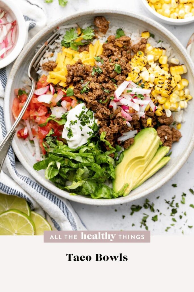Delicious Taco Bowls made with lean ground beef, cilantro lime rice, and all the best toppings! You'll love how quickly this recipe comes together and it's perfect to meal prep for lunch or dinner!