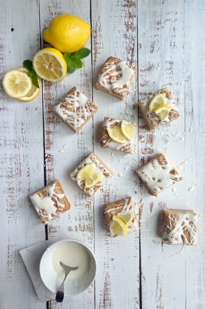 Lemon blondies cut into squares with a bowl of lemon glaze