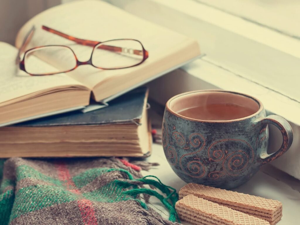 Monday Musings, returning after loss, a mug of tea, a pile of books, and a plaid blanket