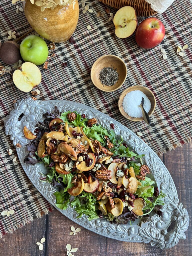 Roasted apple salad with pecans, cranberries aon a pewter platter with acorns and acorn leafs surrounded by apples