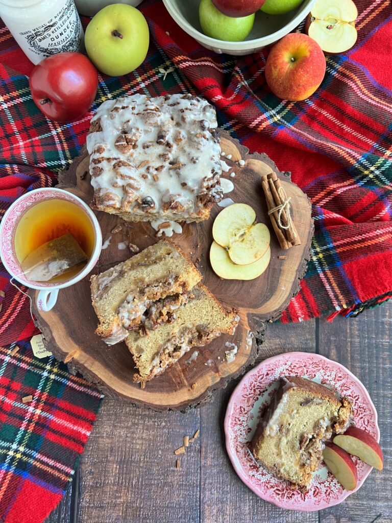 Sliced apple bourbon loaf cake with pecan streusel on a wooden board. with a cup of tea