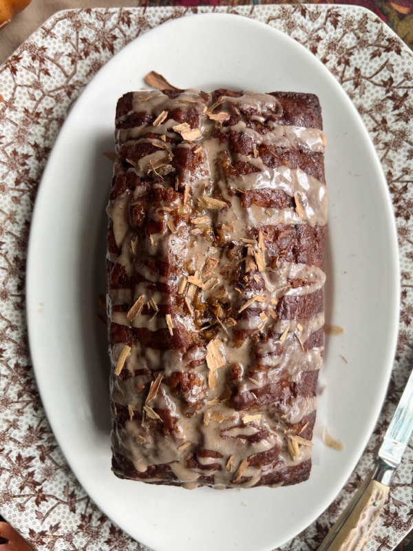 Pumpkin banana bread with cinnamon glaze on an oval ivory plate.