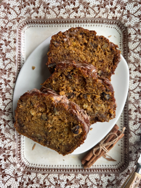 Three slices pumpkin banana bread on brown and white transfer ware.